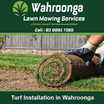 Hands in gloves placing a roll of grass turf in Wahroonga